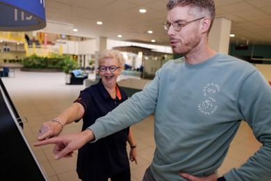vrijwilliger die patient helpt bij aanmeldzuilen